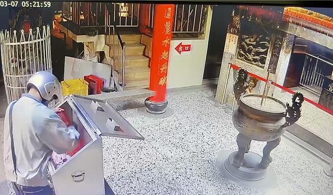 陈姓窃贼破坏竹山紫南宫乐捐箱的锁头后，再将香油钱装进红色塑胶袋。（民眾提供／杨静茹南投传真）