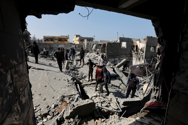 加薩中部城市迪爾巴拉（Deir Al-Balah）一處民宅18日遭以色列空襲之後，居民回到現場查看。（路透）