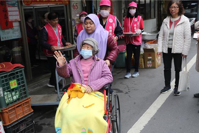 行動不便的長輩在外籍移工的陪伴下，也到三民社區參加共餐。（圖／新北市社會局）