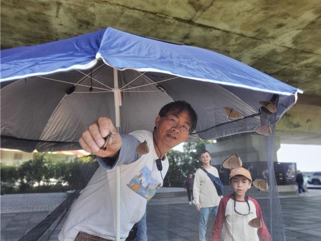台湾紫斑蝶生态保育协会理事长陈瑞祥（左）在蝶帐旁解说紫斑蝶生态。（周丽兰摄）