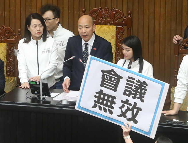 立法院25日院会，民进党立委霸占主席台杯葛议事，随后民进党立委在晚上6点依法定开会时间已到离开议场，但立法院长韩国瑜（后中）依《立法院议事规则》规定，至委员质询结束为止，在晚间7点20继续开会，虽然民进党团抗议会议无效，最后仍在国民党和民眾党人数优势下，表决闯关成功，径付二读后交付协商。（赵双杰摄）