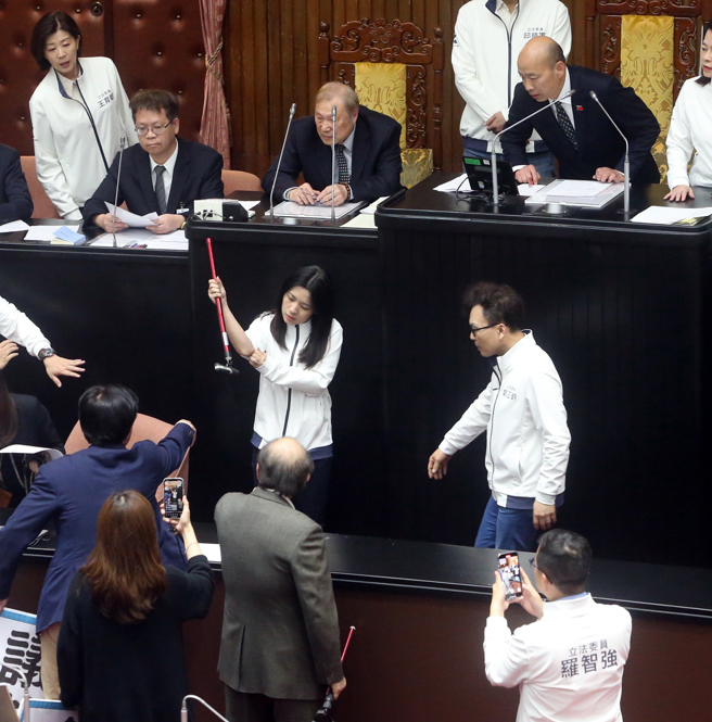 立法院25日院会，民进党立委霸占主席台杯葛议事，随后民进党立委在晚上6点依法定开会时间已到离开议场，但立法院长韩国瑜（后右）依《立法院议事规则》规定，至委员质询结束为止，在晚间7点20继续开会，民进党立院党团总召柯建铭（前中）到场拿起拐杖敲打抗议，不慎将拐杖打断，波及国民党立委徐巧芯（中右二）。（赵双杰摄）