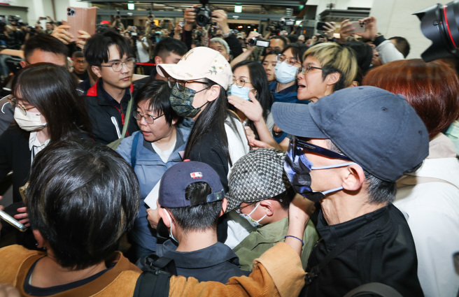 陆配网红刘振亚「亚亚」（中戴白帽者）因公开宣传武统，遭内政部移民署废止其依亲居留许可，并要求她最迟需于25日深夜离境，否则将面临强制遣返。25日晚间，亚亚与孩子及老公现身松山机场在航空公司柜台办理手续，将搭乘晚间20时45分厦门航空的班机前往福州。（陈俊吉摄）
