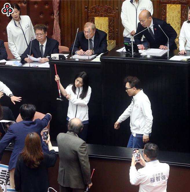 立法院25日院会，民进党立委霸占主席台杯葛议事，在空转一整天后，立法院长韩国瑜（后右）依《立法院议事规则》规定，在晚间7点20继续开会，处理国民党团所提的反废死、反戒严公投，民进党立院党团总召柯建铭（前中）到场拿起拐杖敲打抗议，不慎将拐杖打断，波及国民党立委徐巧芯（中右二）。（赵双杰摄）