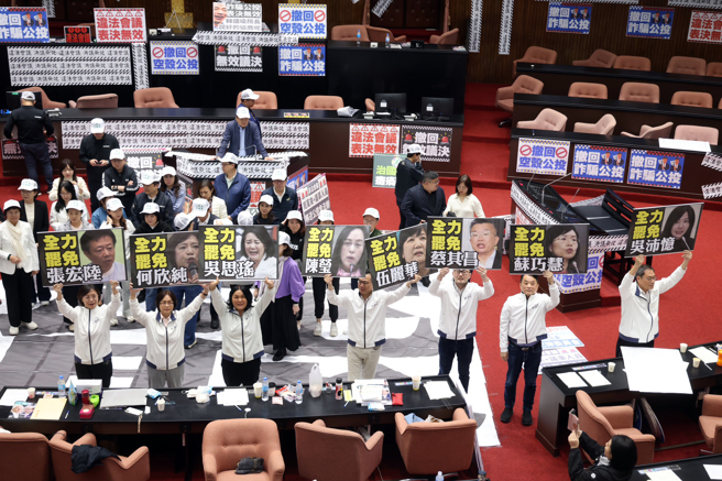 民進黨團為阻擋25日院會議事錄確認，28日占據議場主席台，讓議事停擺一整天，直至晚間6點多綠營立委集合在議場中，多位藍委則拿著一階達罷免門檻的8位民進黨立委看板，雙方各自呼口號叫陣。（鄧博仁攝）