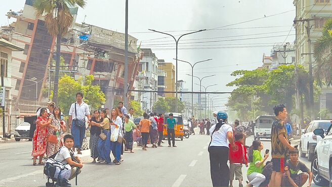 缅甸大地震，多栋建物被震毁，民眾惊慌失措站在街道上，望着受损的家园。（路透）