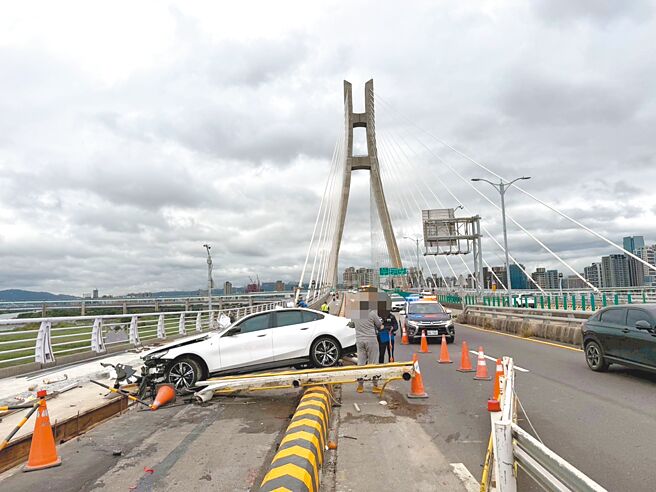1辆白色BMW i5纯电轿车29日自撞新北大桥施工护栏，造成1名义交右脚骨折。（三重警分局提供／张铠乙新北传真）