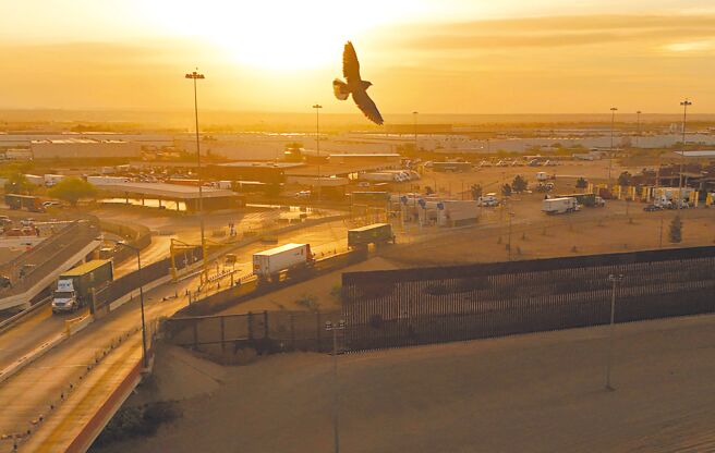 图为2日从墨西哥华雷斯城，由无人机拍摄的卡车穿过美墨边境大桥进入美国境内的情景。（路透）