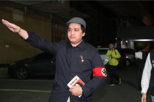 李坤城罢免团体领衔人宋建梁穿着象徵纳粹的「卐」字臂章，手比纳粹敬礼手势，还拿着希特勒着作「我的奋斗」进入侦查大楼。（陈君玮摄）