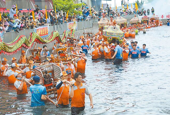 嘉義縣布袋鎮新塭嘉應廟一年一度「衝水路、迎客王」祭典24日登場，吉時一到，神轎依序衝進水裡，將無形客王迎上岸做客。（呂妍庭攝）
