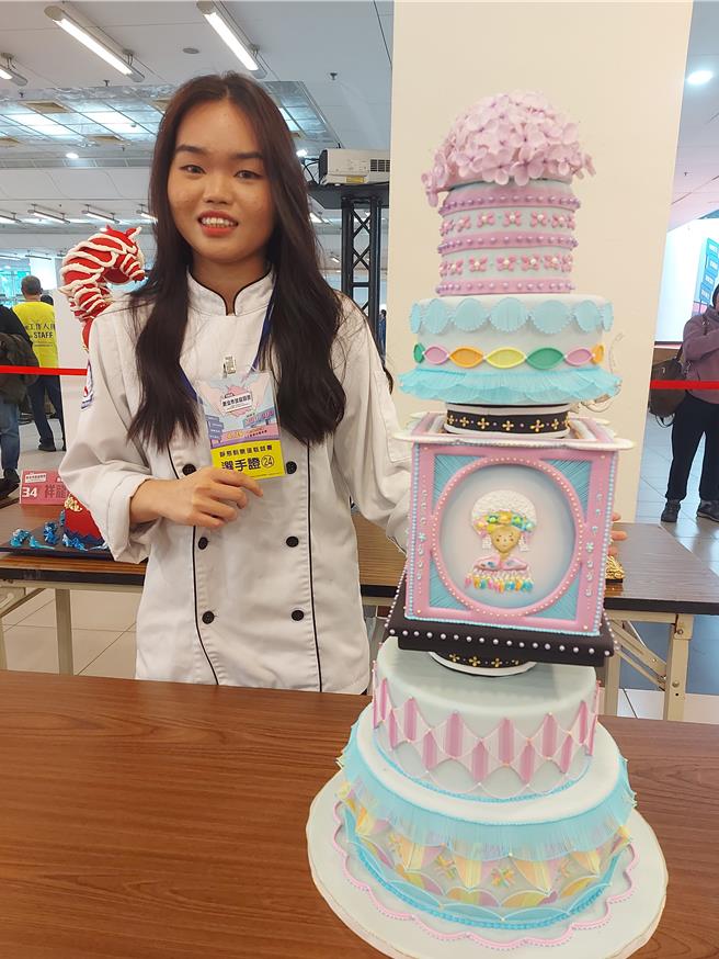 铭传大学餐旅管理学系学生蔡玟萱和制作的「原艺绽放」蛋糕合影。（张铠乙摄）