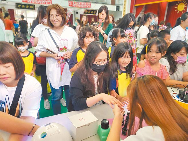 西螺文昌国小趁1日劳动节庆祝母亲节，让不用上班的妈妈们体验当1天公主，图为一位妈妈享受美甲服务。（周丽兰摄）