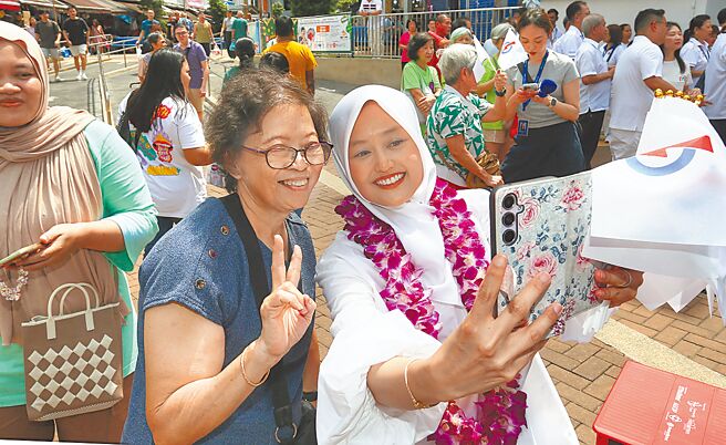 星国大选落幕，总理黄循财「大考」过关，成功守住执政地位。面对新一轮美中贸易战，黄循财挑战才刚开始。图为新加坡人气颇高的拉哈尤议员（右）亲切回应民眾的支持。（郑任南摄）
