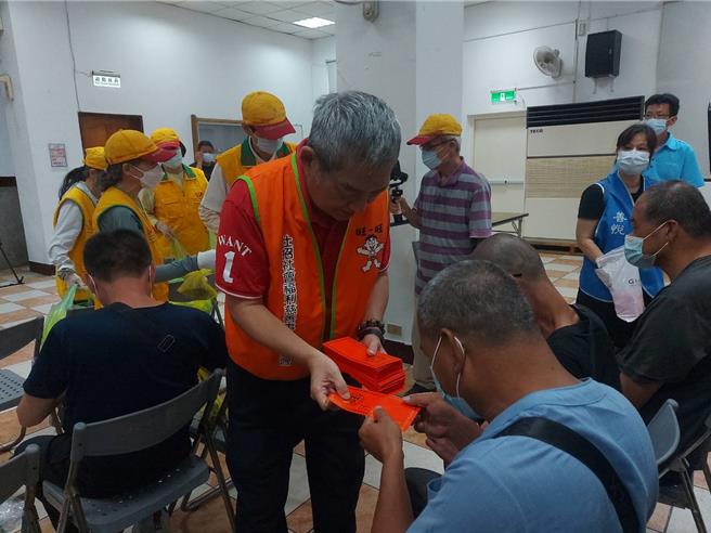 仕招社会福利慈善基金会课长周哲仁（中）致赠红包给街友。（张铠乙摄）