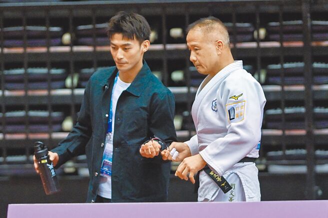 「柔道男神」杨勇纬的教练刘文等（右），21日出席双北世壮运柔道男子73公斤级M6（55至59岁）赛事，杨勇纬（左）则以指导教练身分在场边指导；杨帮刘收好眼镜，感情深厚。（郭吉铨摄）