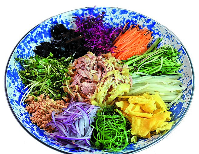 「风生水起贵妃捞鸡」源于顺德名菜「风生水起」，「屾淼苑」以鸡肉丝取代鱼肉，搭配葱丝、小黄瓜、红萝卜丝、木耳丝、薄脆、花生碎与白芝麻，加入特调红油提味。图／姚舜