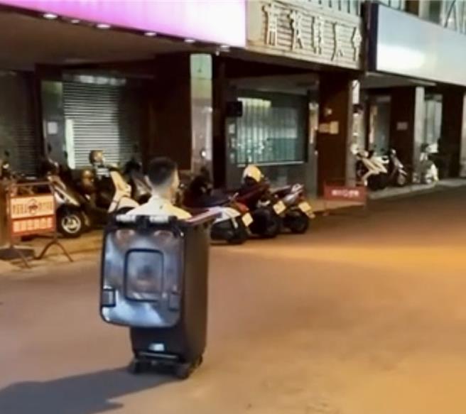 男子10日晚间8时多坐进黑色大垃圾桶内沿街滑行，引起热议。（民眾提供／杨静茹南投传真）