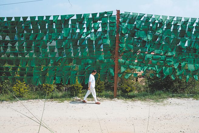 仁波切独行在山门口。一旁的是整片的绿色风马旗。绿色乃仁波切本命对应的顏色。（摄影／林彦廷）