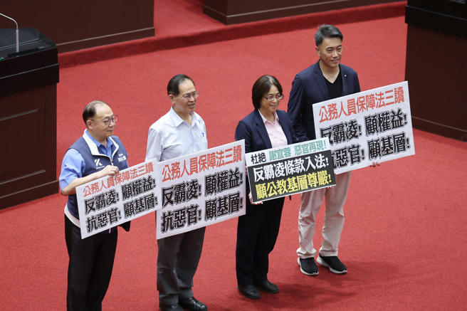 立法院24日院會三讀通過「公務人員保障法部分條文修正草案」，國民黨立委在議場內拿著標語合影留念。（姚志平攝）