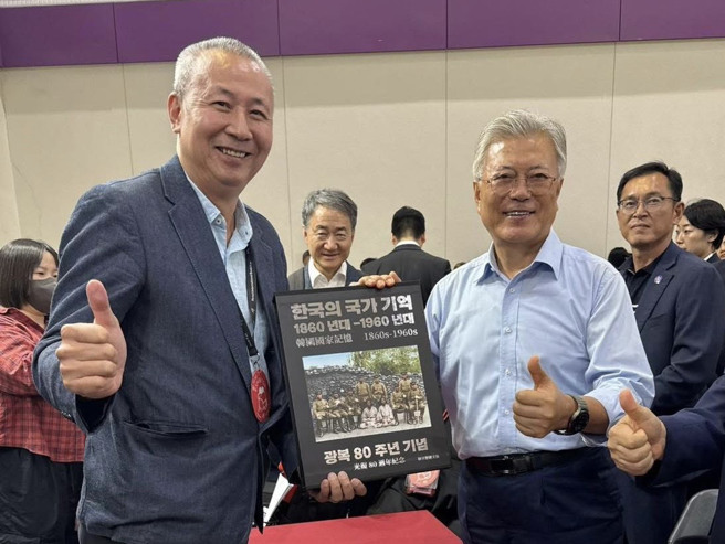 首尔国际书展上，韩国前总统文在寅（右）拿着作者徐宗懋（左）出版的画册《韩国国家记忆，1860s-1960s-光復80周年纪念》合影。（图／徐宗懋提供）