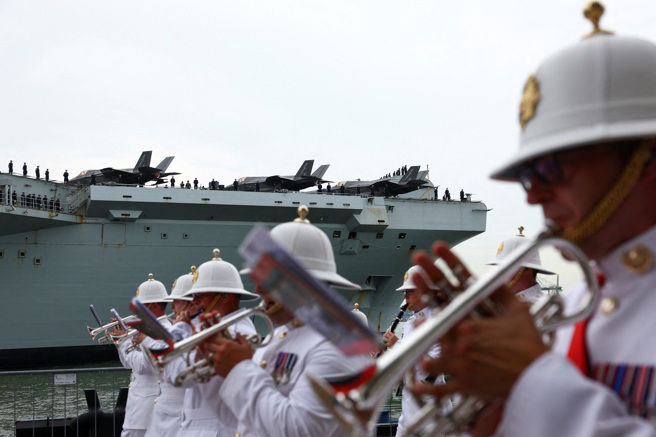英國皇家海軍航空母艦「威爾斯親王號」（HMS Prince of Wales）23日抵達新加坡，軍樂隊在岸邊表演，艦上的F-35戰機吸引大眾目光。（路透）