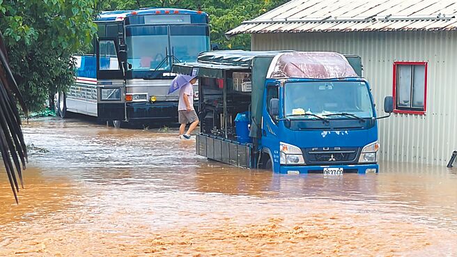 受低壓帶與西南風影響，台東縣大武鄉太湖路排水溝暴漲溢流，積水深及車輪，人車涉水而行，宛如在「陸上黃河」中通行。（蕭嘉蕙攝）