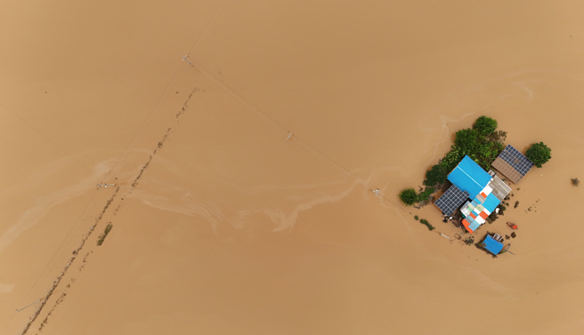 南韓中部16日起發生致災強降雨，忠清南道禮山郡多處嚴重淹水，一處民宅只剩頂樓與屋頂露出水面。（路透）