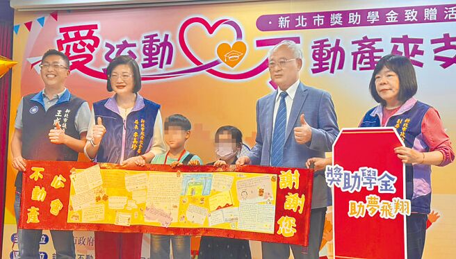 获得奖学金的学生们手写感谢卡，献给新北市不动产开发商业同业公会理事长廖志鸿（右二），并与市议员王威元（左一）、社会局长李美珍（左二）及副局长吴淑芳（右一）合影。（张铠乙摄）