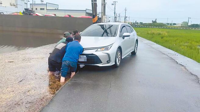 有民眾开车行经彰化县伸港乡曾家村一处道路，右前轮陷进水田中，附近工厂老板与5名越南籍移工见状，合力协助车子脱困。（赖清美提供／叶静美彰化传真）