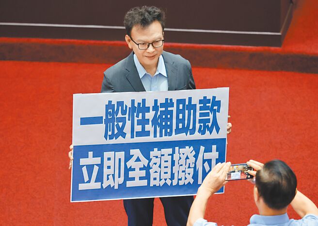 國民黨立委鄭正鈐8日拿著「一般性補助款，立即全額撥付」標語，呼籲行政院立即撥付地方政府一般性補助款。（姚志平攝）