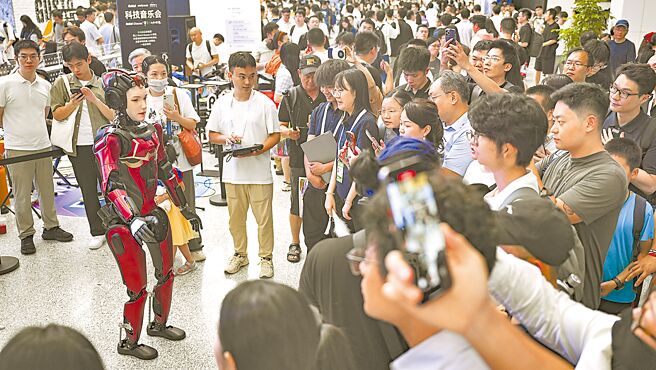 大陸駐美國大使謝鋒22日表示，AI是人類共同財富，中美應攜手加強企業人才交流。圖為「上海2025世界人工智能大會」，參觀者在圍觀一款人形機器人。（新華社）