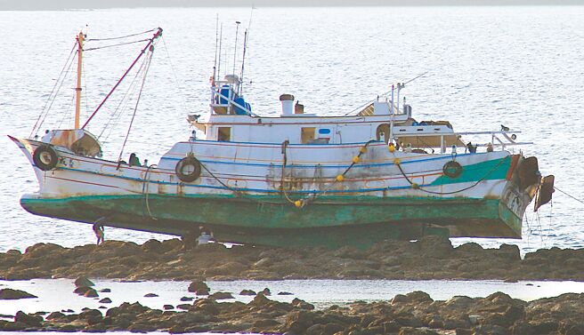 澎湖当地造船厂师傅26日登上礁石，检视触礁搁浅的渔船破损情形。（许逸民摄）