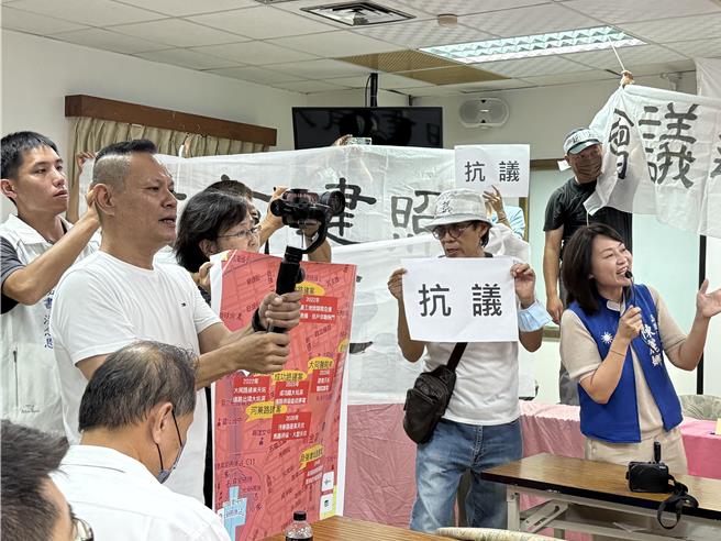 国宾不当容积自救会、居民等30多人举着手牌在高雄国军英雄馆2楼怒抗议，认为高市府今日举办拆除国宾饭店说明会不合理，要求说明会立即停办。（纪爰摄）