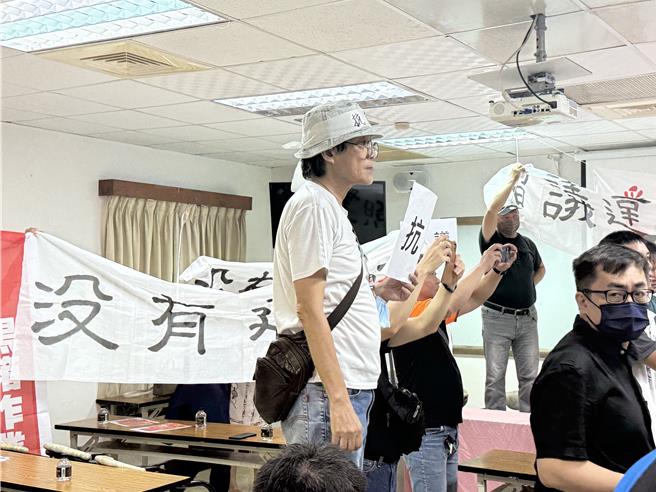 国宾不当容积自救会、居民等30多人举着手牌在高雄国军英雄馆2楼怒抗议，认为高市府今日举办拆除国宾饭店说明会不合理，要求说明会立即停办。（纪爰摄）