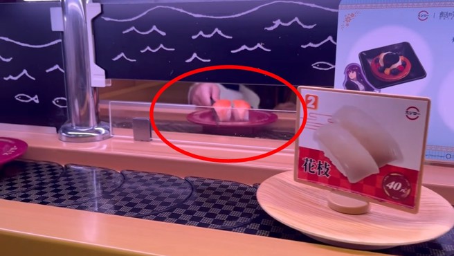 迴轉壽司店內，小屁孩疑似用使用過的筷子，擋在壽司前面，阻擋壽司前進，遭網友錄影。（翻攝爆怨公社）