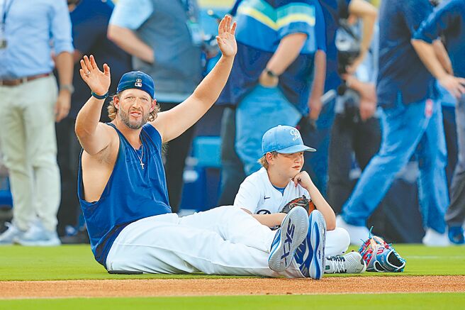 道奇左投柯萧（左）宣布引退决定后，与儿子查理坐在草皮上。（美联社）