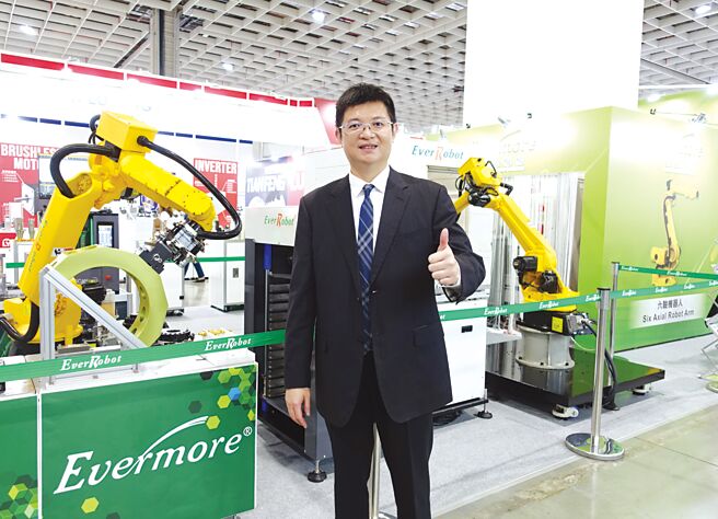 勤堃机械总经理廖河诚和该公司的机械手臂合影。图／黄俊荣