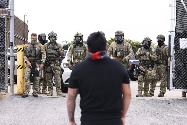 2025年9月19日，芝加哥一名示威民眾，站在美國移民與海關執法局（ICE）面前。（美聯社）