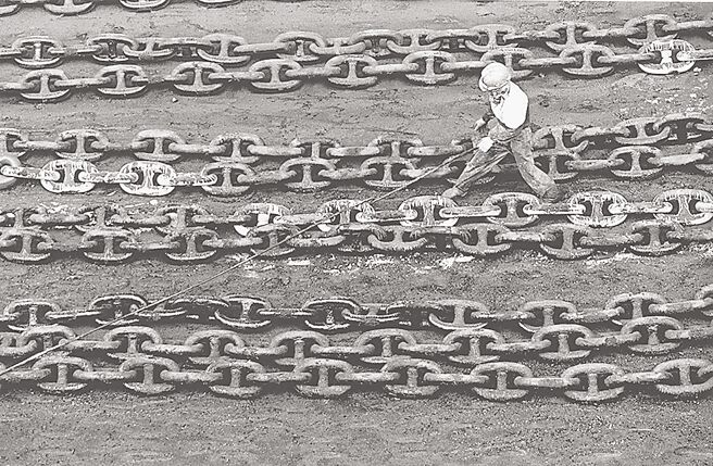 〈中船〉一条条的锚炼铺陈在地上，这些硕大的炼条是轮船下锚用的，在大船进港后，平日用以固定巨大船身的炼条，也需要好好保养，它们横列在陆地上，等待被好好整理后，准备下一次的出航。（谢三泰摄／国家摄影文化中心提供）