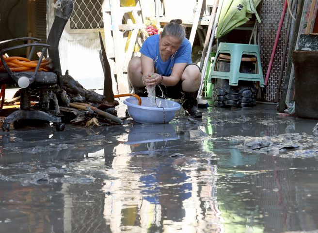 馬太鞍溪堰塞湖溢流造成嚴重災情，民眾忙著清理家園，一位婦人蹲坐在家門口，仔細地清洗家中物品。（范揚光攝）
