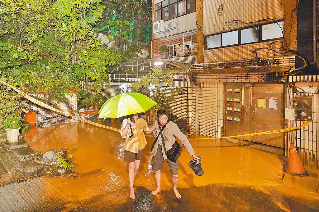 台北市文山區景華街後山邊坡21日晚間土石滑落,連夜疏散6戶,民眾涉水離開住家。(杜宜諳攝)