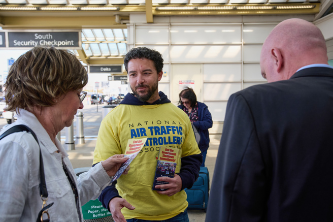 美国维吉尼亚州雷根机场航管人员日前向旅客发小册子，说明因政府关门，导致他上班却无法支薪。（资料照/美联社）