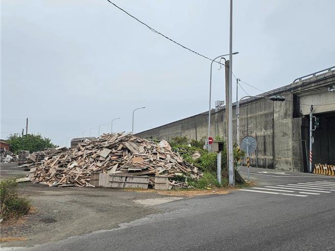 台61线公路下方堆置的模板恐会被强风吹到路面影响交通，居民通知区公所派员处理。（民眾提供／郭良杰台南传真）
