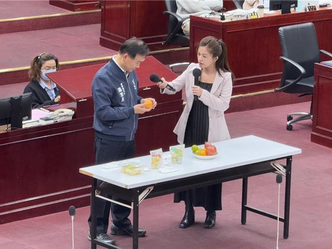 学校营养午餐多提供如芭乐、百香果等水果，须靠刀子截切才有办法食用，北市议员洪婉臻(右)请北市教育局长汤志民(左)尝试食用「整颗水果」，她说，也许大人能够靠剥来食用，但对于低年级学生该如何是好。（张珈瑄摄）