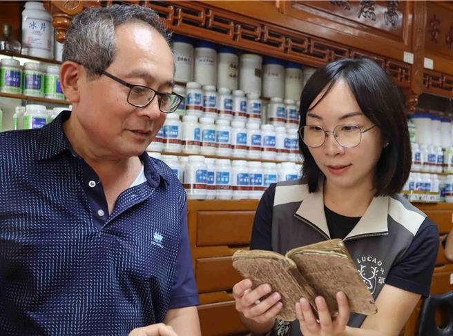 鹿草乡长严佩瑜（右）小心翻看王家祖传手抄药方。（吕妍庭摄）