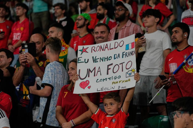 2025年10月14日，在里斯本举行的2026年世界杯F组葡萄牙对匈牙利的足球比赛前，一名男孩举着牌子请求与C罗合影。（图／美联社）