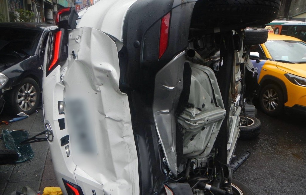 一輛自小客車駕駛疑似精神不濟，完全未注意前方已有三輛汽車在停等紅燈，竟直接猛力追撞，導致前車如骨牌般連續推撞，更造成其中一輛被撞的車輛當場側翻，還波及路邊兩台無辜機車。（圖／簡銘柱翻攝）