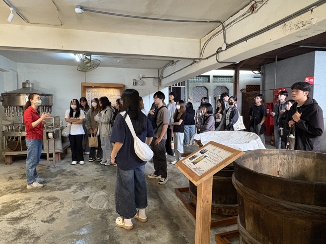 南華大學至「丸莊醬油」參訪，同學們聆聽黑豆醬油的釀造過程。(南華大學提供)