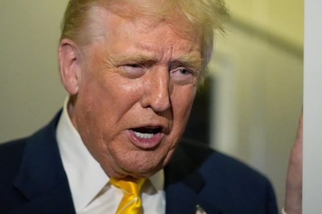 美國總統川普14日在「空軍1號」專機上發表談話的神情。（美聯社）