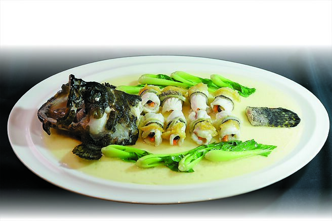 「玉樹芙蓉龍虎斑」是將龍虎斑魚肉切片，捲入切絲的香菇、紅蘿蔔和芹菜與韭黃為餡後清蒸，並用魚湯煨柚子點綴提味，盤底襯的是魚高湯蒸蛋。圖／姚舜